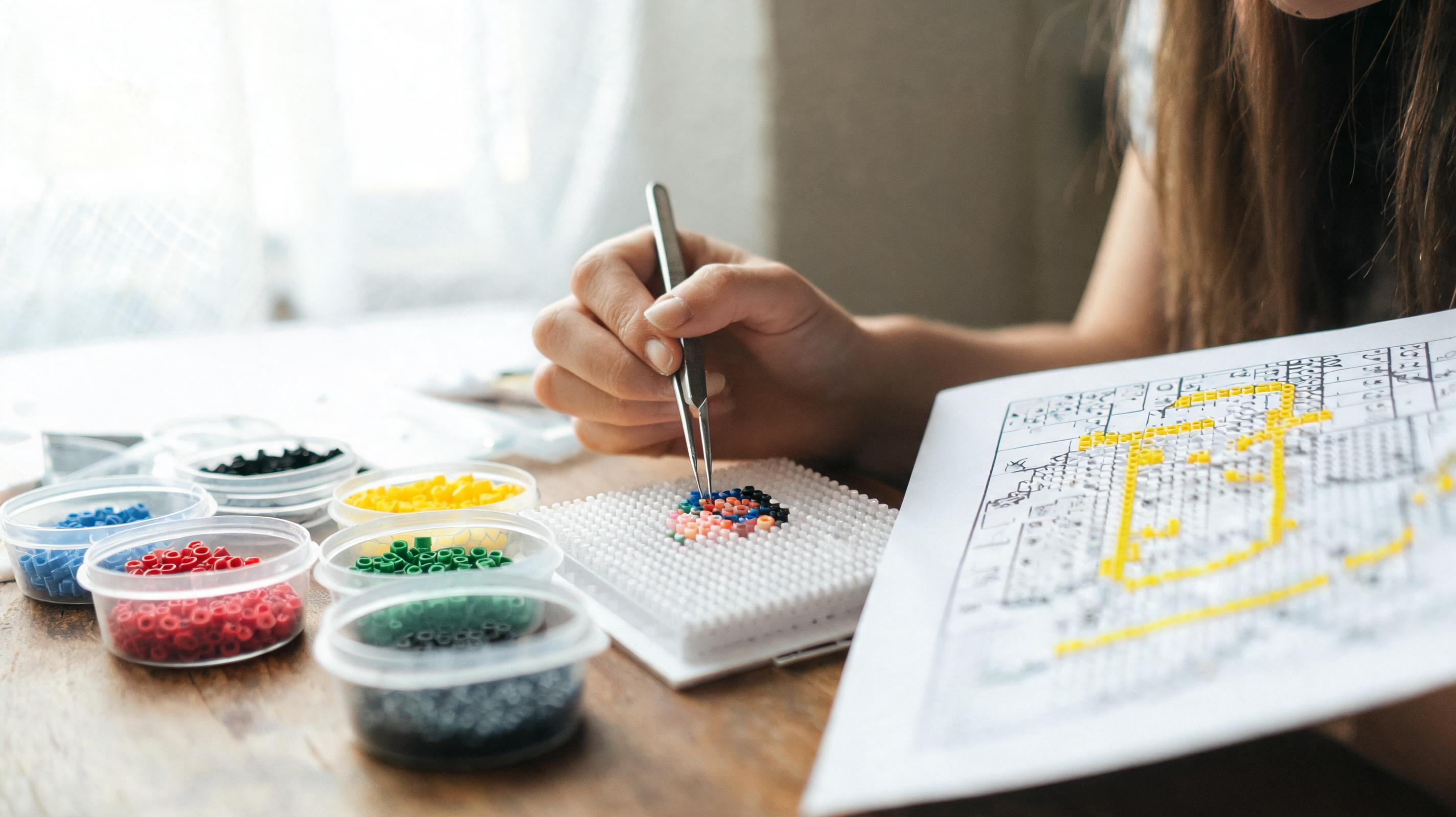 Crafter following a printed bead pattern on a peg board